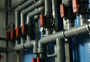 Commercial Plumbing with grey PVC pipes and multiple valves with red handles