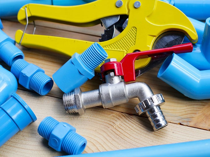 Blue PVC pipes and fittings with a steep valve and PVC cutting tool
