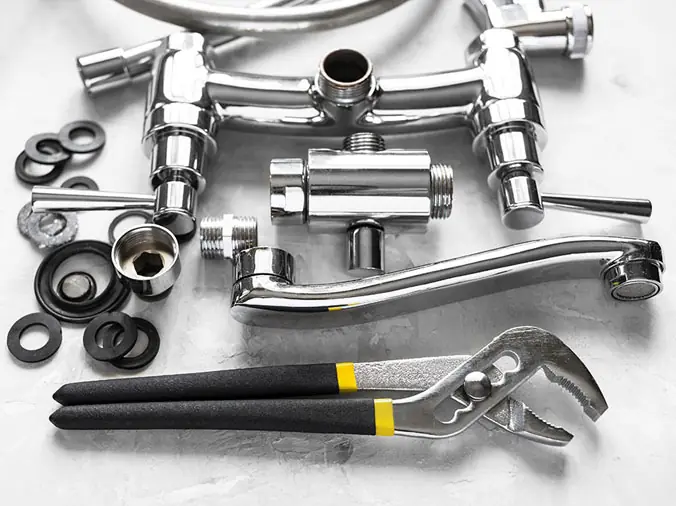 Polished chrome sink parts with a wrench in the foreground